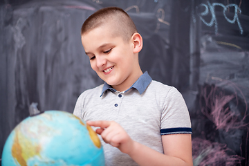 Image showing boy using globe of earth in front of chalkboard