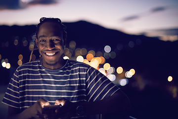 Image showing Young  Afro man on  street at night using phone