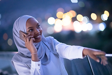 Image showing Young Muslim woman on  street at night using phone