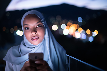 Image showing Young Muslim woman on  street at night using phone