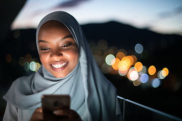 Image showing Young Muslim woman on  street at night using phone