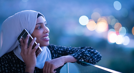 Image showing Young Muslim woman on  street at night using phone