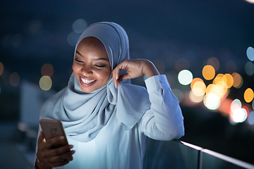 Image showing Young Muslim woman on  street at night using phone