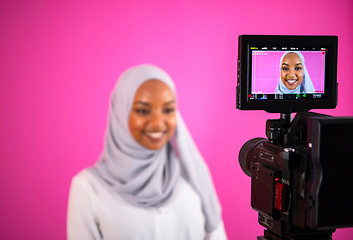 Image showing videographer in pink studio recording video on professional came