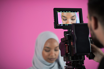 Image showing videographer in pink studio recording video on professional came