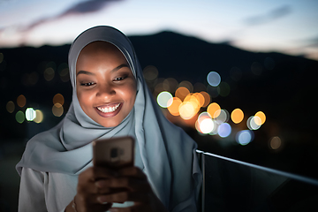 Image showing Young Muslim woman on  street at night using phone