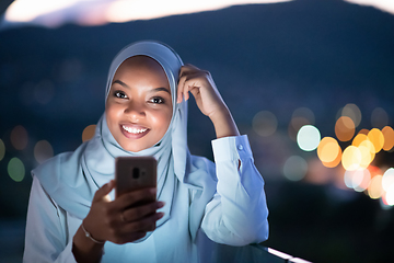 Image showing Young Muslim woman on  street at night using phone