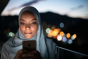 Image showing Young Muslim woman on  street at night using phone