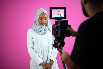 Image showing videographer in pink studio recording video on professional came