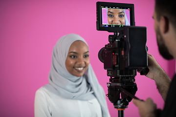 Image showing videographer in pink studio recording video on professional came