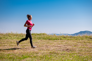 Image showing young woman jogging on sunny day at summer mountain