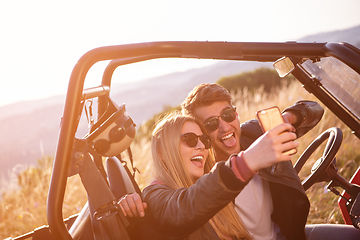 Image showing young couple taking selfie picture while driving a off road bugg