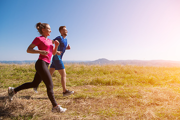 Image showing young couple jogging on sunny day at summer mountain