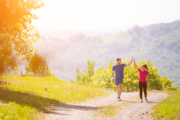 Image showing jogging couple giving high five to each other on sunny day at na