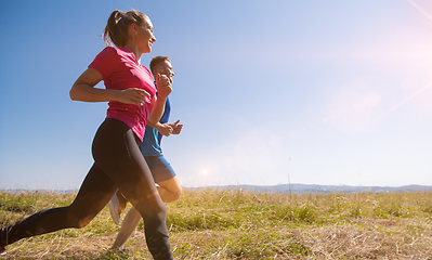 Image showing young couple jogging on sunny day at summer mountain