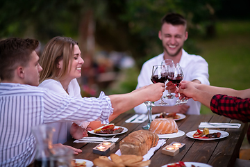 Image showing happy friends toasting red wine glass during french dinner party