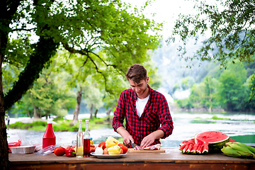 Image showing Man cutting meat for barbecue grill