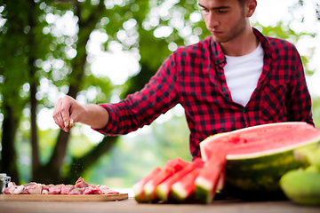 Image showing Man putting spices on raw meat  for barbecue grill