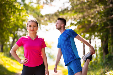 Image showing young couple warming up and stretching on sunny day at nature