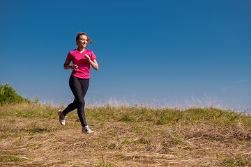 Image showing young woman jogging on sunny day at summer mountain