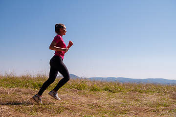 Image showing young woman jogging on sunny day at summer mountain