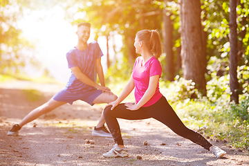 Image showing young couple warming up and stretching on sunny day at nature