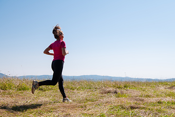 Image showing young woman jogging on sunny day at summer mountain