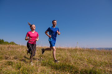 Image showing young couple jogging on sunny day at summer mountain