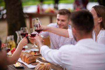 Image showing happy friends toasting red wine glass during french dinner party