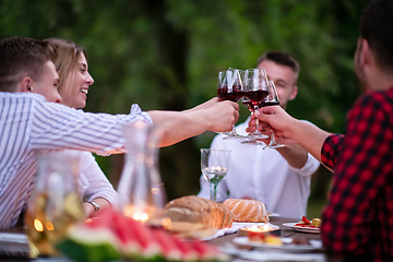 Image showing happy friends toasting red wine glass during french dinner party