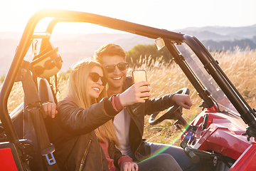 Image showing young couple taking selfie picture while driving a off road bugg