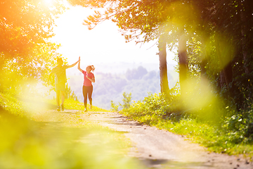 Image showing jogging couple giving high five to each other on sunny day at na