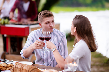 Image showing happy couple toasting red wine glass during french dinner party 