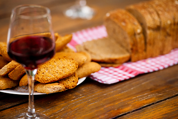 Image showing glass of red wine and toasted bread on wooden table