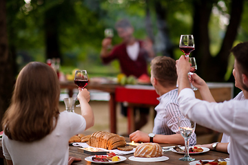 Image showing happy friends toasting red wine glass during french dinner party