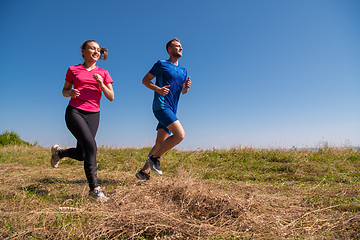 Image showing young couple jogging on sunny day at summer mountain