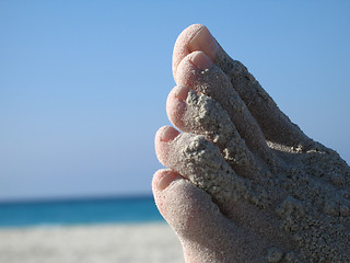 Image showing female foot covered with sand