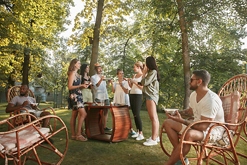 Image showing Happy friends eating and drinking beers at barbecue dinner on sunset time