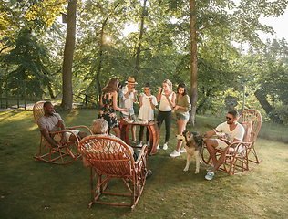 Image showing Happy friends eating and drinking beers at barbecue dinner on sunset time