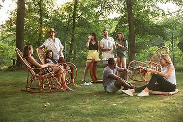 Image showing Happy friends eating and drinking beers at barbecue dinner on sunset time