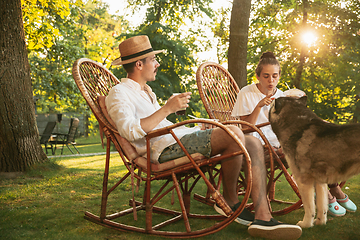 Image showing Happy couple eating and drinking beers at barbecue dinner on sunset time