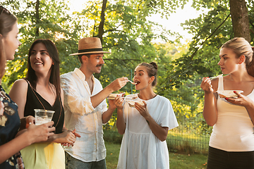 Image showing Happy friends eating and drinking beers at barbecue dinner on sunset time