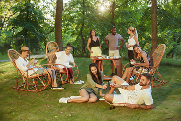 Image showing Happy friends eating and drinking beers at barbecue dinner on sunset time