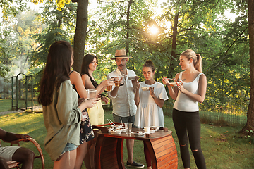 Image showing Happy friends eating and drinking beers at barbecue dinner on sunset time