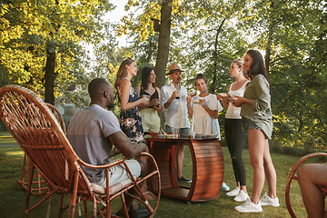 Image showing Happy friends eating and drinking beers at barbecue dinner on sunset time