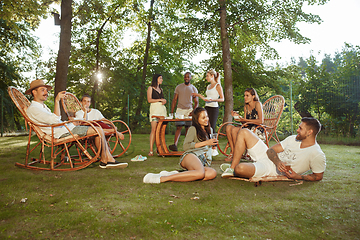 Image showing Happy friends eating and drinking beers at barbecue dinner on sunset time