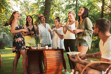 Image showing Happy friends eating and drinking beers at barbecue dinner on sunset time