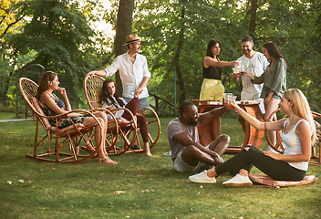 Image showing Happy friends eating and drinking beers at barbecue dinner on sunset time