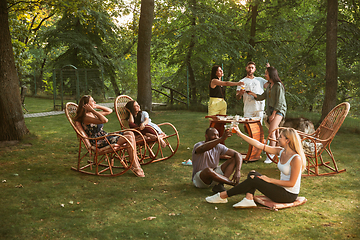 Image showing Happy friends eating and drinking beers at barbecue dinner on sunset time