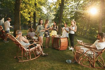 Image showing Happy friends eating and drinking beers at barbecue dinner on sunset time